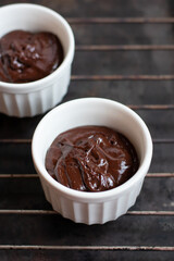 Chocolate dough for fondant in the white ramekin on dark background. Making french dessert. Lava...