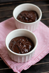 Chocolate dough for fondant in the white ramekin on dark background. Making french dessert. Lava cake.
