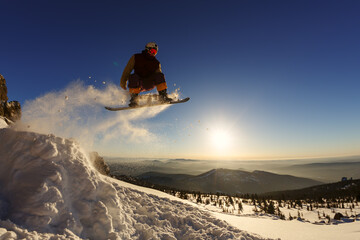 Snowboarder jumping through air with deep blue sky in background