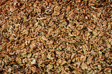 Heap of dried brown organic walnut kernels displayed for sale at a street food market, top view or flat lay of tasty healthy food photographed with soft focus