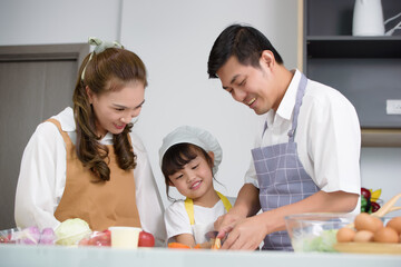 Asian family enjoy with cooking together salad foods homemade in kitchen room at modern home. Create activities together in the family. Soft focus on center children.