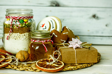 Homemade Christmas Food Gifts.Homemade cookies nuts, gingerbread, a jar of honey, dried oranges, a mixture for baking cookies in a jar on a wooden background. The concept of cozy, soulful DIY gifts