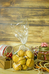 Handmade Christmas gifts. Cookies nuts, a jar of honey, dried oranges, a box with a gift, tapes for packaging on a wooden background. The concept of Christmas edible gifts.