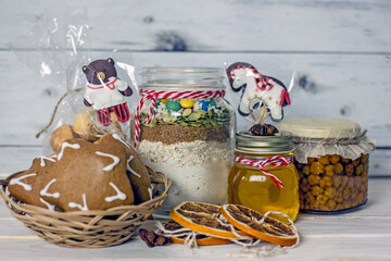 Homemade Christmas Food Gifts.Homemade cookies nuts, gingerbread, a jar of honey, dried oranges, a mixture for baking cookies in a jar on a wooden background. The concept of cozy, soulful DIY gifts