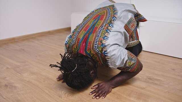 African Man In The House Bowing Down And Worshipping Salah Salat Muslim Prayer medium shot. High quality photo