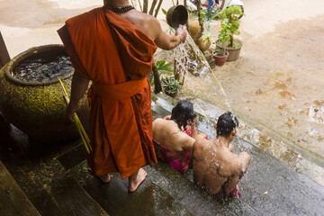 a monk pours water over worshipers to bless them at a temple in siem reap, cambodia