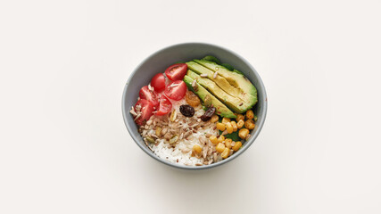 Top view of healthy vegetable bowl lunch with cherry tomatoes, avocado, corn, rice and seeds isolated over white background