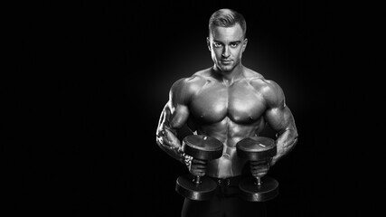 Fototapeta na wymiar Black and white vertical photo of perfect fit athletic guy workout. Handsome power athletic man with a naked torso in training pumping up muscles with dumbbells in a gym. Fitness muscular body