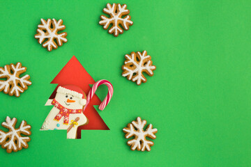 Christmas tree cut out on a green background and gingerbread snowman