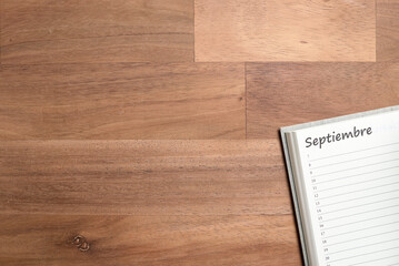Blank page of a daily planner in Spanish for the month of September, wooden desk