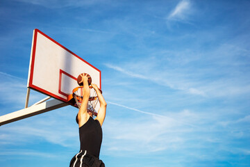 Young man jumping and making a fantastic slam dunk playing streetball, basketball. Urban authentic.