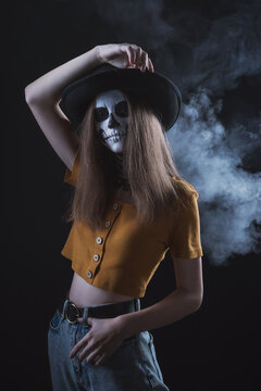 Girl with a skeleton make-up on her face on a dark background with a sad expression