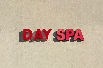 Day Spa sign logo in red letters on beige concrete wall