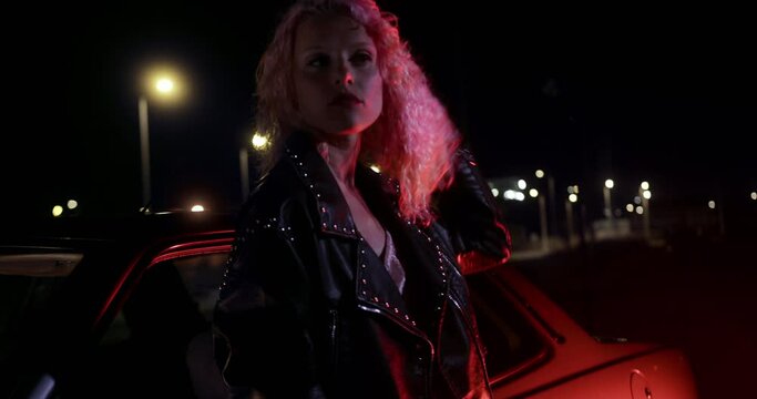 Pink hair young woman leaning on car chewing gum
