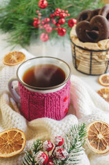 Fototapeta na wymiar Hot winter tea in a red mug with candied oranges and a warm scarf - Christmas rural still life