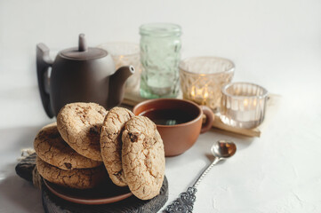 Almond and chocolate homemade cookies on the table with a ceramic Cup of tea and a kettle