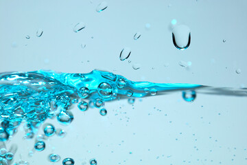 Nahaufnahme einer blauen Wasseroberfläche mit Wassertropfen und Luftblasen.