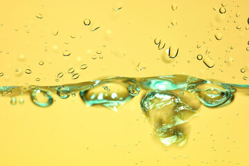 Nahaufnahme einer blauen Wasseroberfläche mit Wassertropfen und Luftblasen.