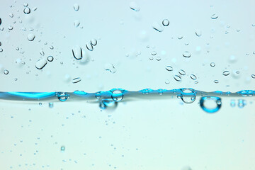 Nahaufnahme einer blauen Wasseroberfläche mit Wassertropfen und Luftblasen.