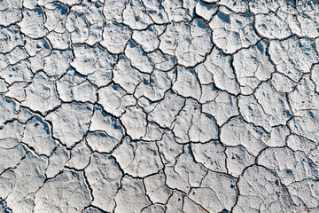 White soil cracked from the drought, top view. Background and texture to illustrate global environmental and climate change issues