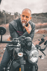 Fototapeta na wymiar Motociclista hombre mexicano en carretera sobre su motocicleta con chaqueta de cuero y botas