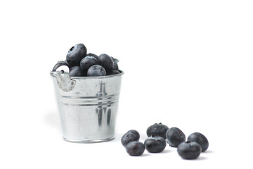 silver bucket of blueberry and a pile of berries isolated on white background. Farming concept.