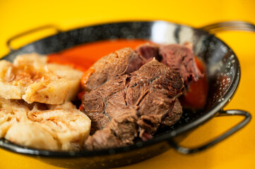 Boiled beef shine, dumpling and tomato sauce in black pan.