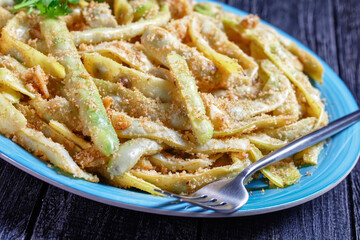 Golden french wax beans on a blue plate, close-up