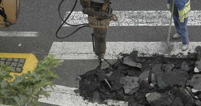 Road reparation. Construction Machine jackhammer breaking asphalt of the road