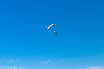 Parachutist is flying in the sky, sunny contrast image.