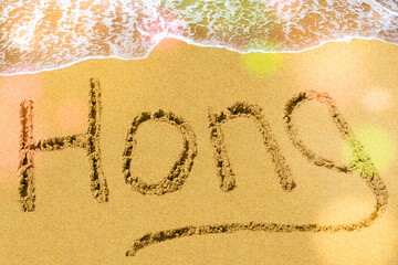 Hong title on the sand beach of the South China sea. Bokeh falls on the letters.