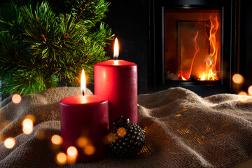 Christmas decorations with log fire and festive bokeh. Atmospheric christmas still life with fir tree and with candlelight on rustic linen sack. Space for your text. 