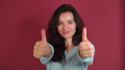 Young beautiful girl shows two thumbs up on a purple background.