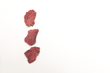 Three pieces of beef tenderloin on a light background with copy space. Top view