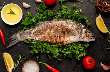 grilled sea bass with spices, herbs, and lemon on a stone background