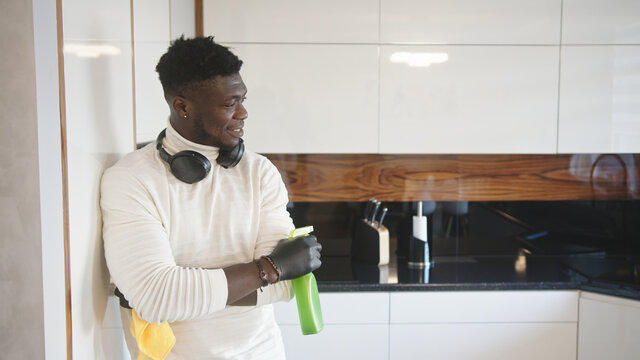 Black man cleaning kitchen. Germaphobe excessively wiping reflective surface. High quality photo