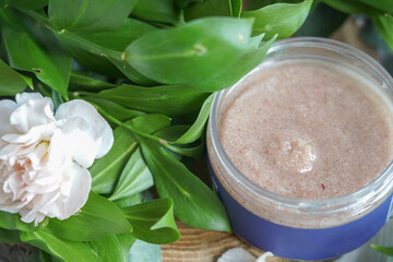 body scrub pink in a jar on a background of flowers
