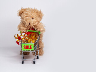 Toy bear holds a small cart with gifts and marked "Sale".