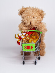 Toy bear holds a small cart with gifts and marked "Sale".