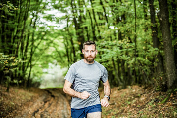 Naklejka na ściany i meble handsome trail runner running in nature