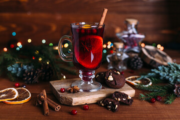 Mulled wine glass with cinnamon and orange. Cookies and fir branches.