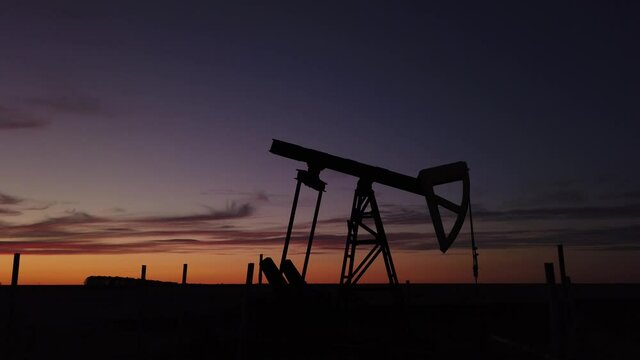 OIL PUMP MACHINE CRANE WITH SUN IN THE BACKGROUND IN CONTRE JOUR