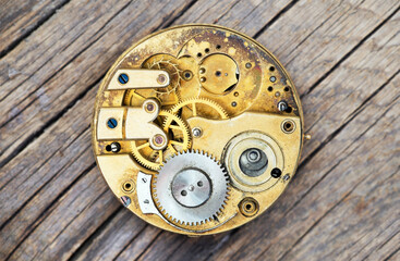 Antique metal pocket watch clockwork with gears on wooden background