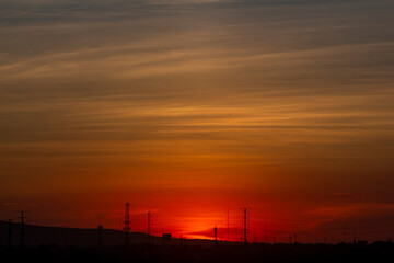 Fototapeta premium Atardecer cielo rojo sol entre torres de luz