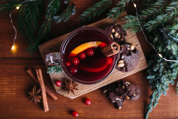 Mulled wine glass with cinnamon and orange. Cookies and fir branches.