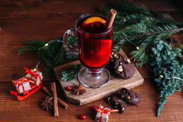 Mulled wine glass with cinnamon and orange. Cookies and fir branches.