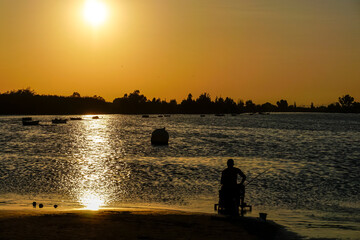 Naklejka na ściany i meble people fishing in the lagoon at sunset