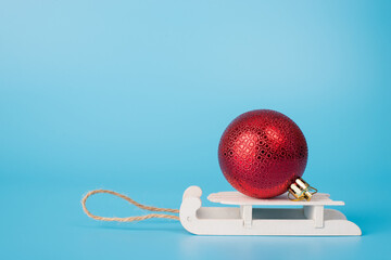 Profile close up photo of one beautiful christmas toy decoration on wooden small sledges isolated over pastel color background with empty blank space