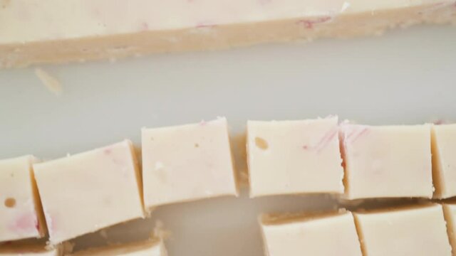 Step by step. Cutting homemade candy cane fudge on a white cutting board.