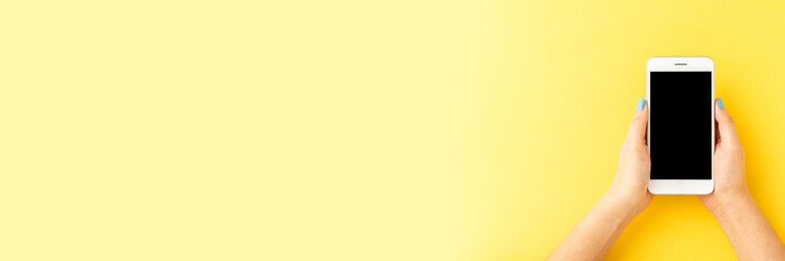 Overhead shot of female hands using mobile phone. Top view. Banner